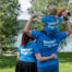 Eine Familie steht mit dem Rücken zur Kamera. Mutter, Vater, Tochter. Die Tochter sitzt auf den Schultern des Vaters. Alle tragen ein blaues Shirt, auf dem Summer Days Velden steht.