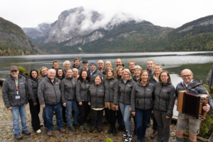 Gruppenfoto Team Höribald. Etwa 25 Personen stehen vor einer Bergszenerie. Sie tragen uniform graue Westen und lächeln in die Kamera.