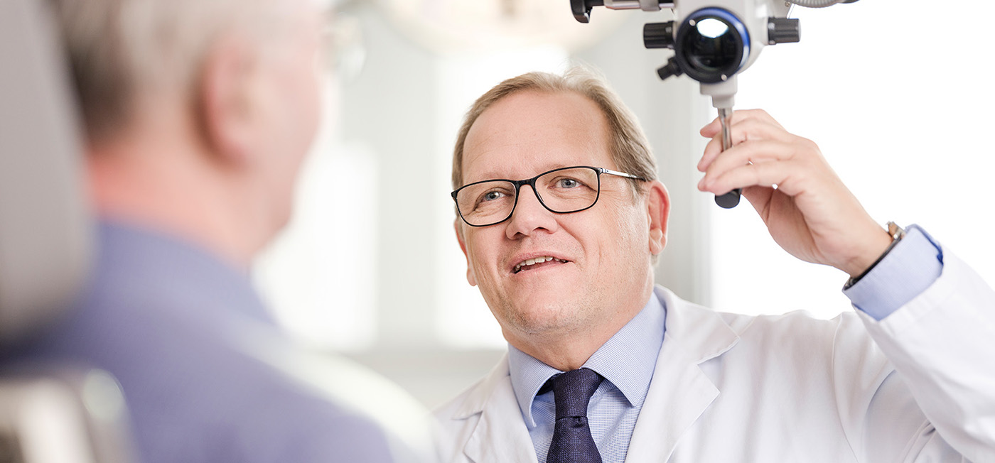 Foto von Prim. Dr. Thomas Keintzel. Ein Mann in den 40ern mit Brille und blondem Haar. Er ist dabei einen Patienten zu untersuchen und schaut deshalb nicht direkt in die Kamera.